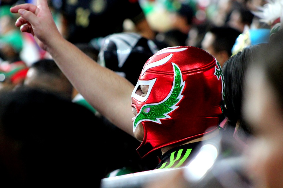 Mexican wrestling fan in the crowd wearing red & green wrestling mask